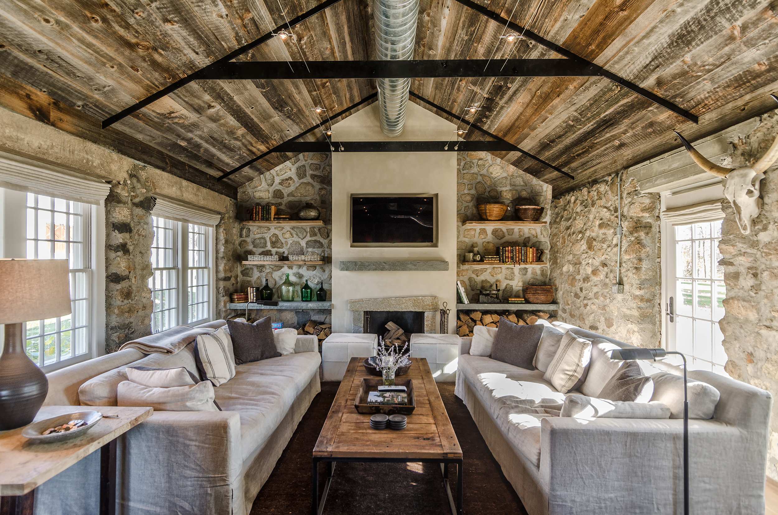 Living room with stone walls and raw wood slatted ceiling 