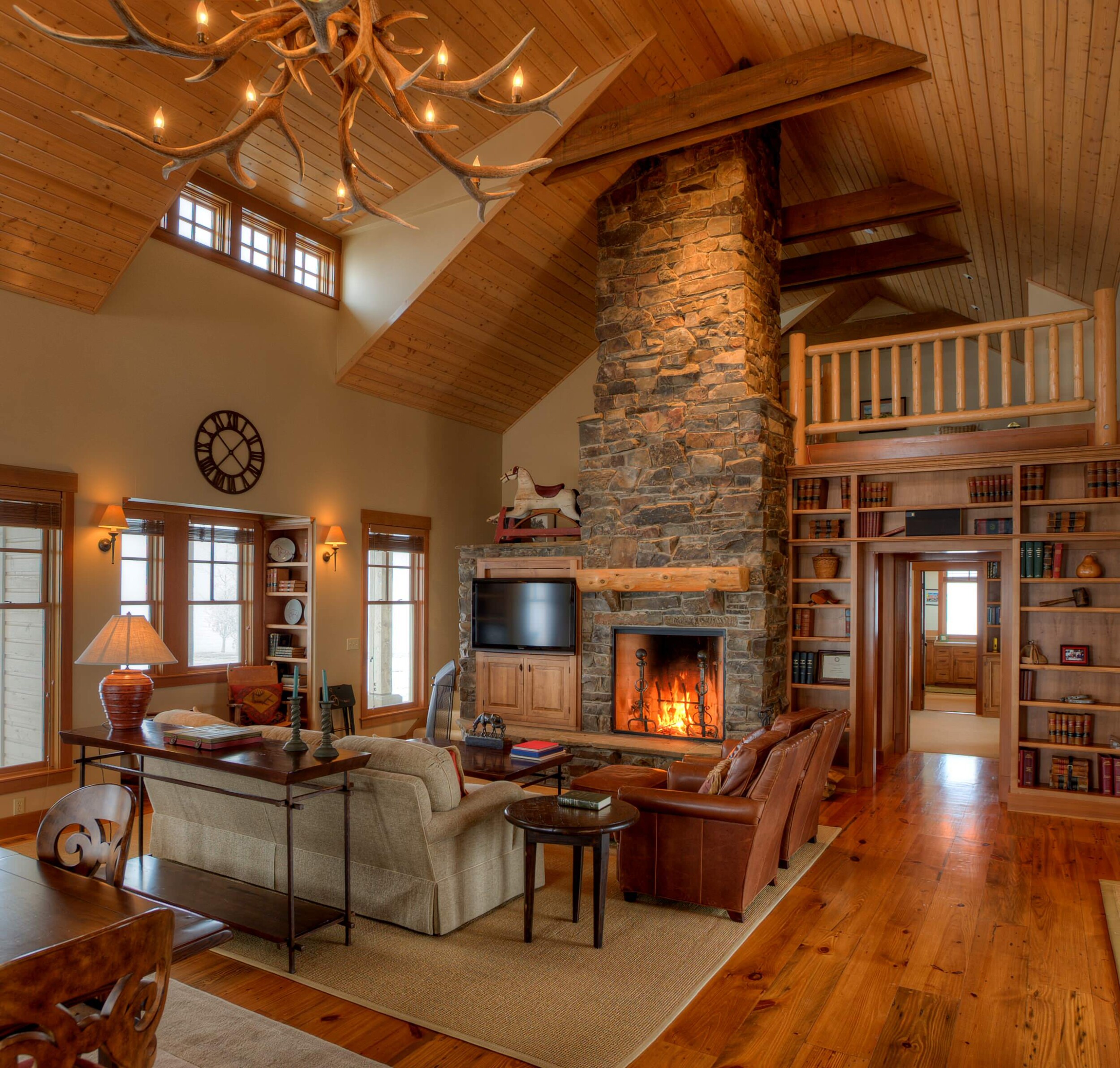 Woodsy living room space with high vaulted ceilings and a fireplace 